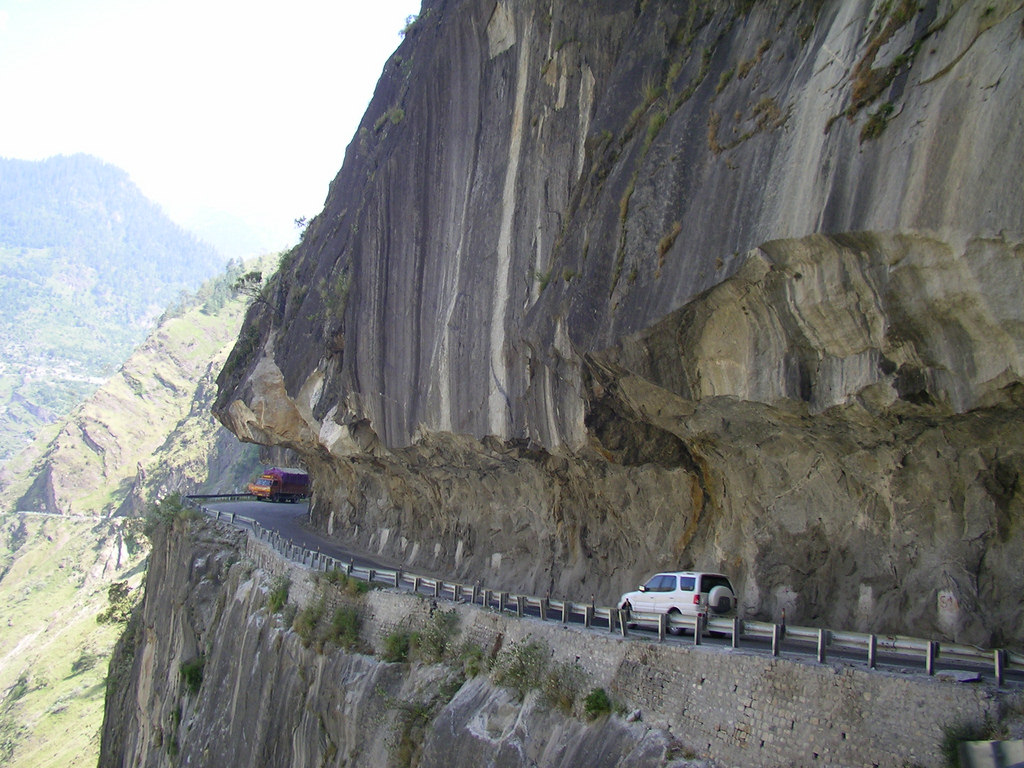 A bus and a truck driving on a very narrow, rocky road in the Himalayas | Yugo Driving School